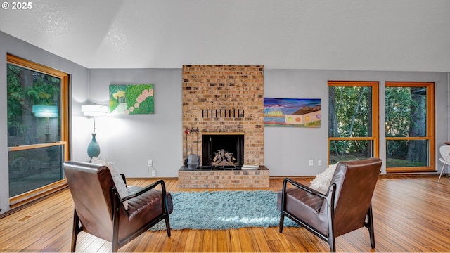 living room with a brick fireplace, hardwood / wood-style floors, and a textured ceiling