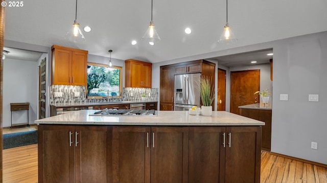 kitchen featuring stainless steel appliances, a kitchen island, decorative light fixtures, and backsplash