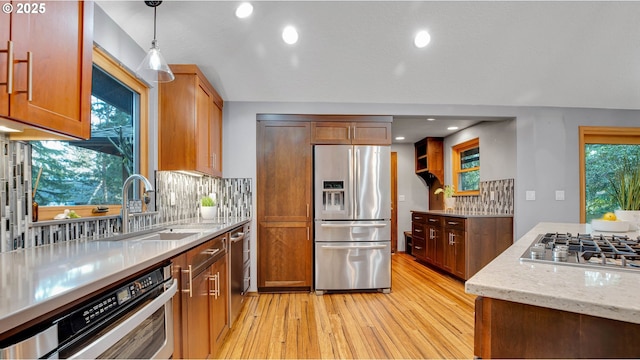 kitchen featuring appliances with stainless steel finishes, backsplash, decorative light fixtures, light stone countertops, and sink