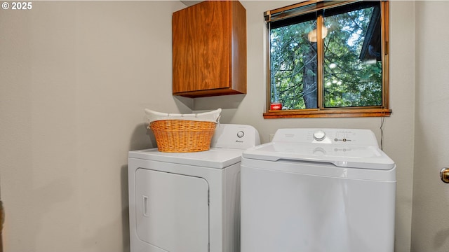 clothes washing area featuring cabinets and separate washer and dryer