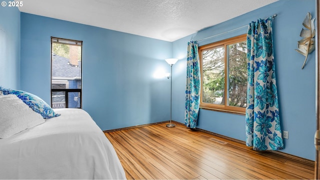 bedroom with hardwood / wood-style flooring, multiple windows, and a textured ceiling