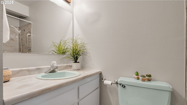 bathroom with toilet, vanity, and a tile shower