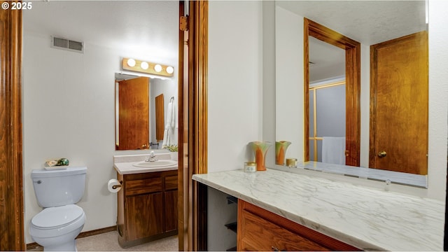 bathroom featuring a shower with shower door, toilet, and vanity