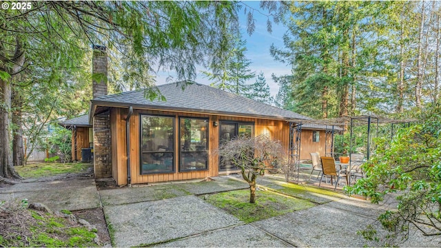 rear view of house with central AC unit and a patio