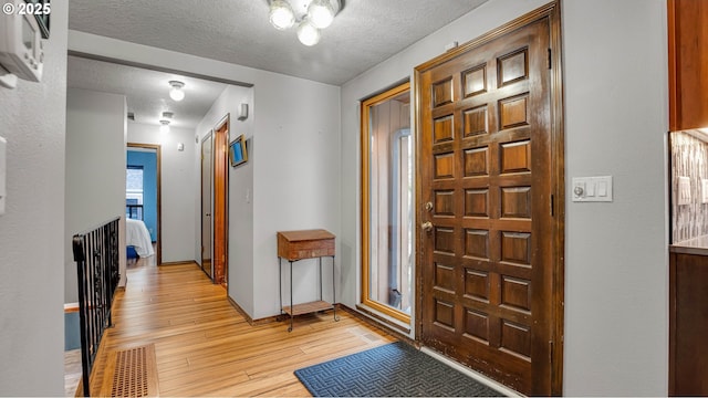 foyer entrance with light wood-type flooring and a textured ceiling