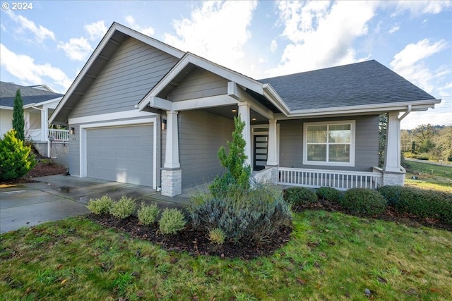 view of front of home with a front yard, a porch, and a garage