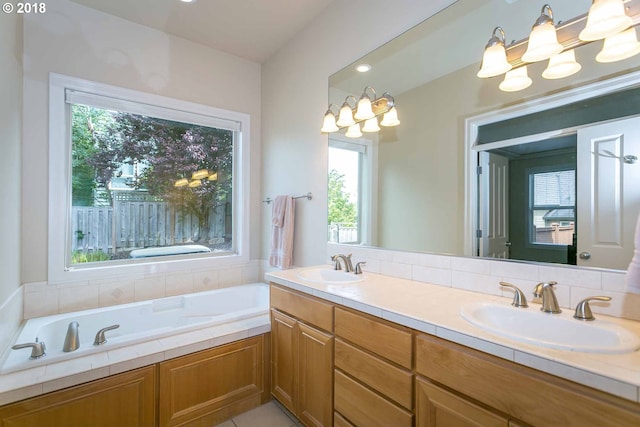 full bath featuring a garden tub, double vanity, and a chandelier