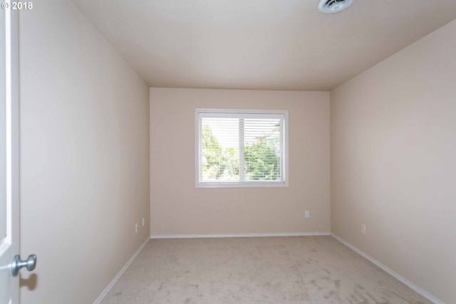 spare room with light colored carpet and baseboards