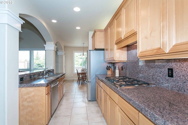 kitchen featuring ornate columns, stainless steel appliances, arched walkways, tasteful backsplash, and light tile patterned floors