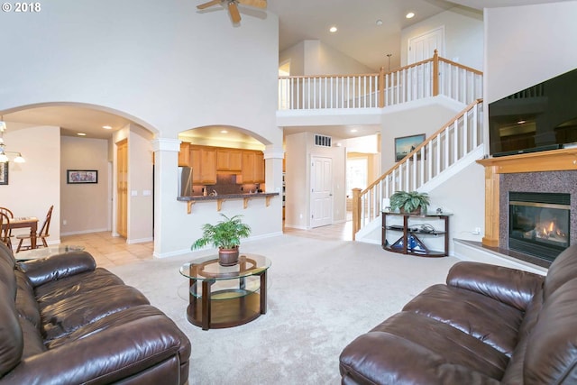 living room with a towering ceiling, arched walkways, ceiling fan, stairs, and ornate columns