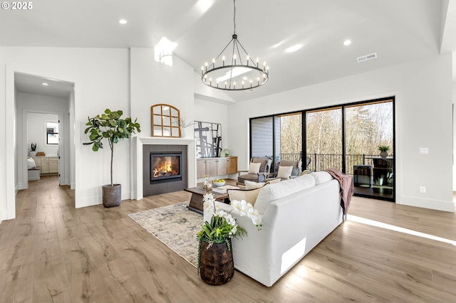 living room with light wood finished floors, visible vents, a tiled fireplace, vaulted ceiling, and recessed lighting