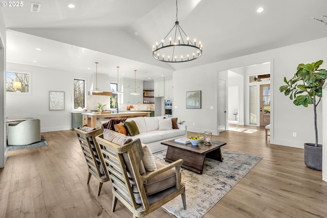 living room with lofted ceiling, visible vents, light wood-style flooring, and recessed lighting