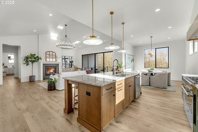 kitchen featuring stainless steel appliances, a center island with sink, open floor plan, and a sink