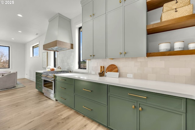 kitchen featuring open shelves, light countertops, high end stainless steel range oven, backsplash, and premium range hood