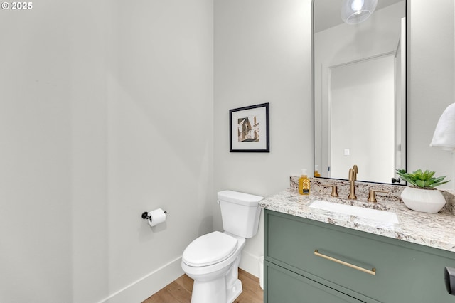 bathroom featuring toilet, wood finished floors, vanity, and baseboards