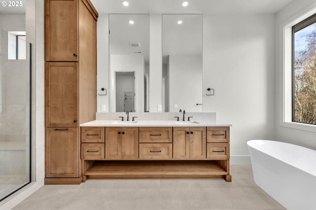 bathroom with double vanity, a soaking tub, a shower stall, and a sink