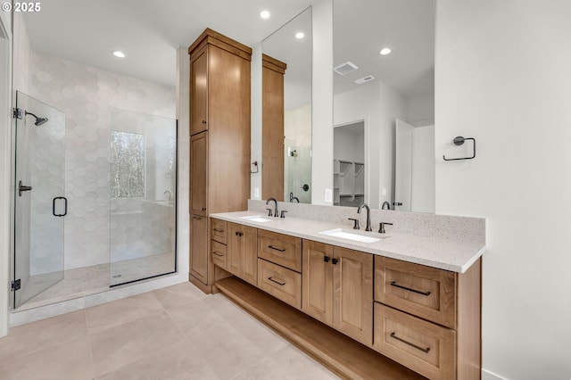 full bathroom with double vanity, a stall shower, a sink, and a walk in closet