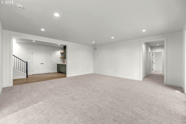 unfurnished living room featuring stairway, carpet, visible vents, and recessed lighting