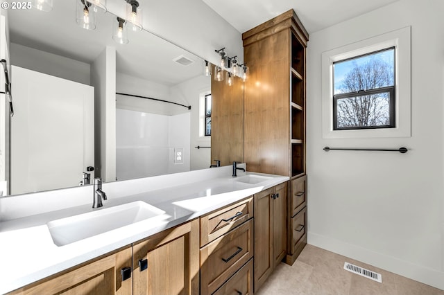 bathroom featuring double vanity, a sink, visible vents, and baseboards