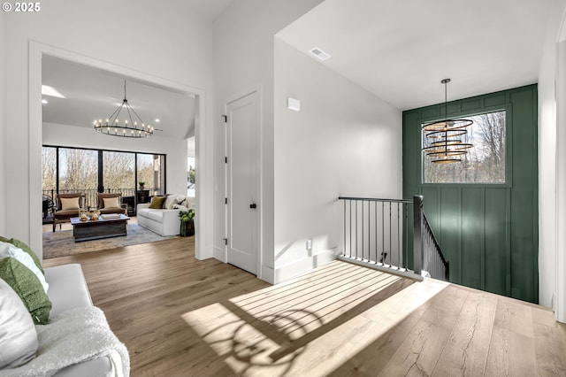 interior space with light wood-style flooring, visible vents, and an inviting chandelier