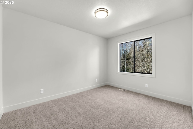 carpeted spare room with visible vents and baseboards