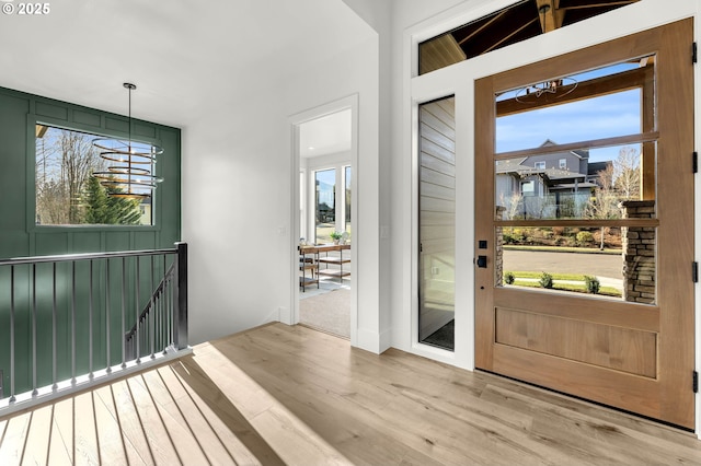 foyer entrance with a chandelier and light wood-style flooring