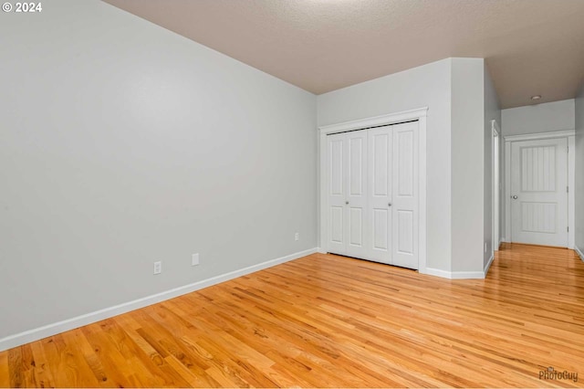 unfurnished bedroom featuring a closet, a textured ceiling, and light hardwood / wood-style flooring