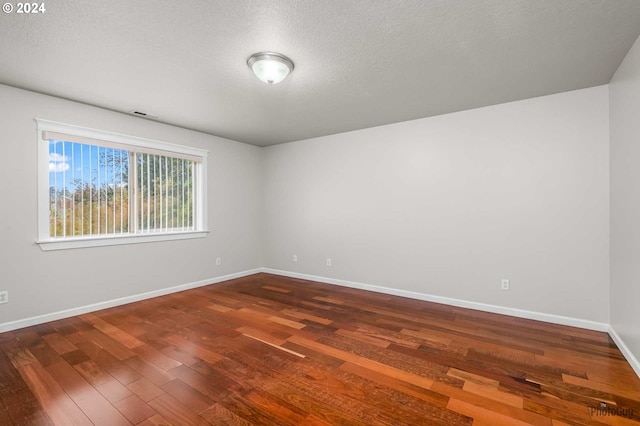 empty room featuring wood-type flooring and a textured ceiling