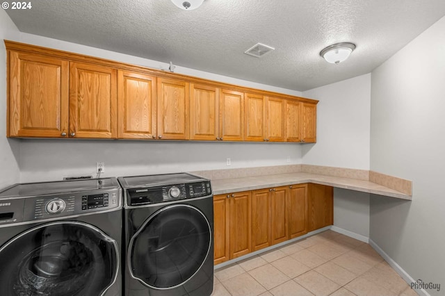 clothes washing area featuring cabinets, washer and dryer, light tile patterned floors, and a textured ceiling