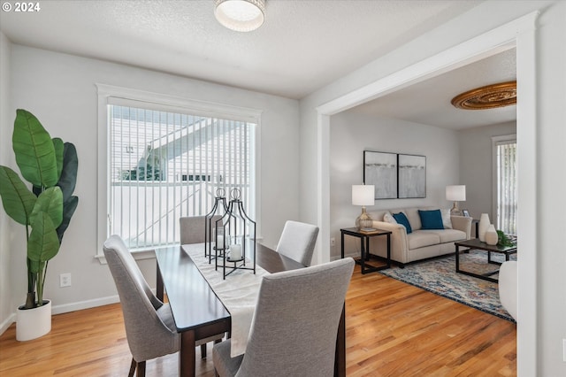 dining area with plenty of natural light, a textured ceiling, and light hardwood / wood-style flooring