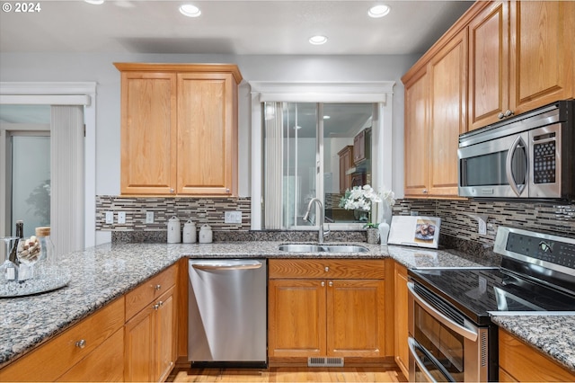 kitchen featuring light stone counters, stainless steel appliances, sink, and tasteful backsplash