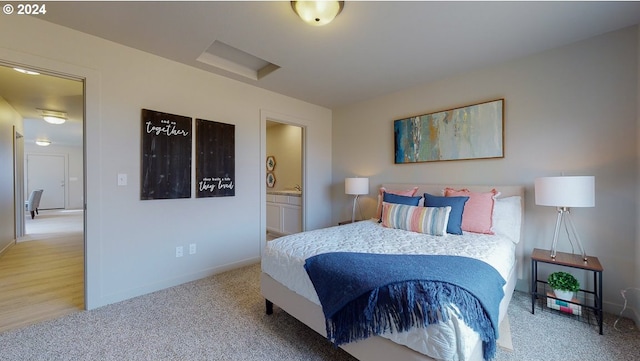 bedroom featuring connected bathroom and light colored carpet