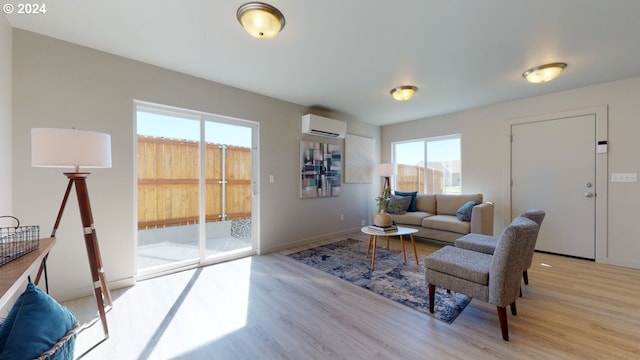 living room with a wall mounted air conditioner and light hardwood / wood-style floors