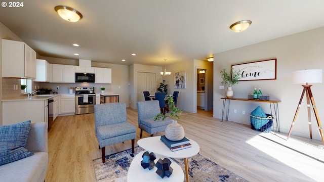 living room featuring light hardwood / wood-style floors, a notable chandelier, and sink