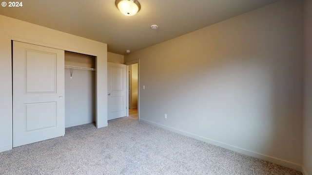 unfurnished bedroom with a closet and light colored carpet