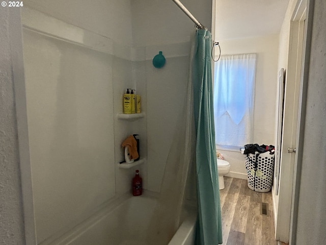 bathroom with toilet, hardwood / wood-style floors, and shower / tub combo with curtain