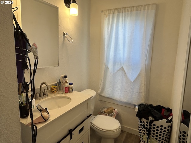 bathroom featuring wood-type flooring, vanity, and toilet