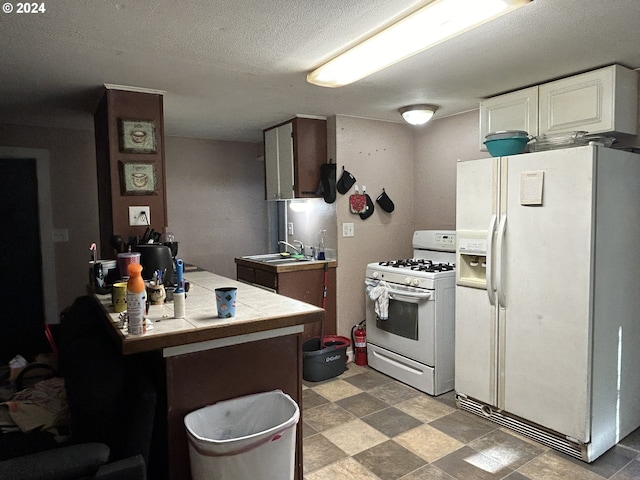 kitchen featuring a textured ceiling, white appliances, tile countertops, and sink