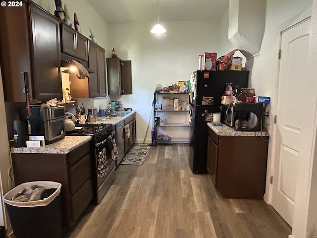 kitchen with dark brown cabinetry, sink, hardwood / wood-style floors, decorative light fixtures, and black appliances