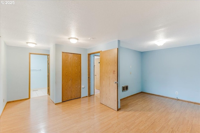 unfurnished room featuring a textured ceiling and light hardwood / wood-style flooring