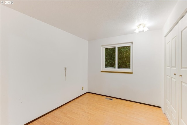 unfurnished room with light hardwood / wood-style floors and a textured ceiling