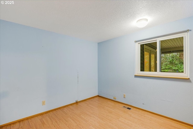 spare room featuring a textured ceiling and light hardwood / wood-style flooring