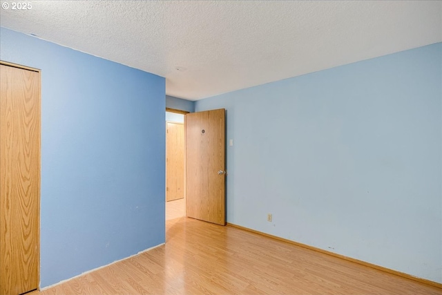 unfurnished room with light hardwood / wood-style floors and a textured ceiling