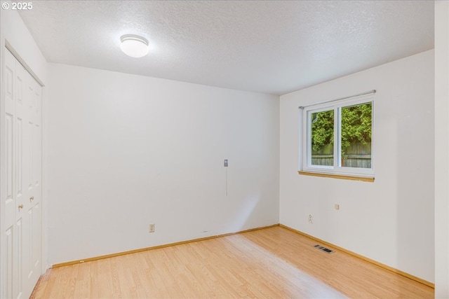 spare room featuring hardwood / wood-style flooring and a textured ceiling