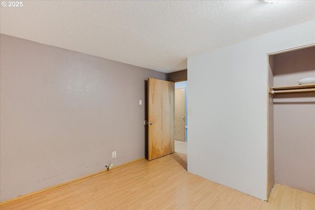 unfurnished bedroom with a closet, light wood-type flooring, and a textured ceiling