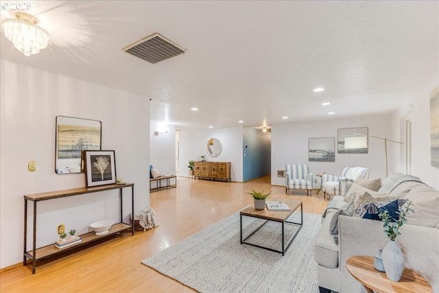 living room featuring a textured ceiling, hardwood / wood-style floors, and a chandelier