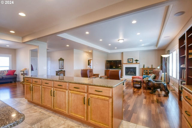 kitchen featuring light tile floors, a tray ceiling, and light stone countertops