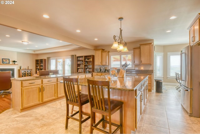 kitchen with a kitchen island, plenty of natural light, stainless steel fridge, and light tile floors