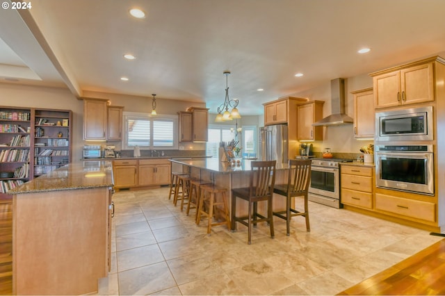 kitchen featuring appliances with stainless steel finishes, dark stone counters, wall chimney range hood, a center island, and light tile floors