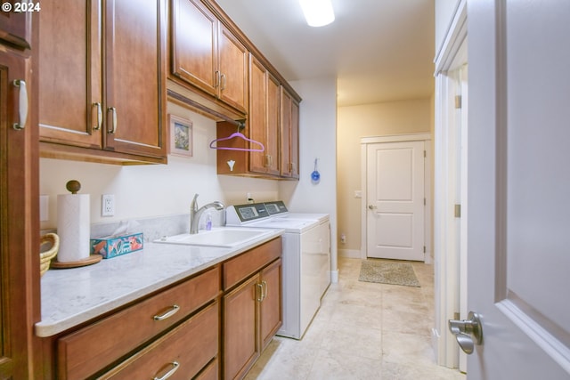 laundry area featuring sink, washing machine and dryer, cabinets, and light tile floors